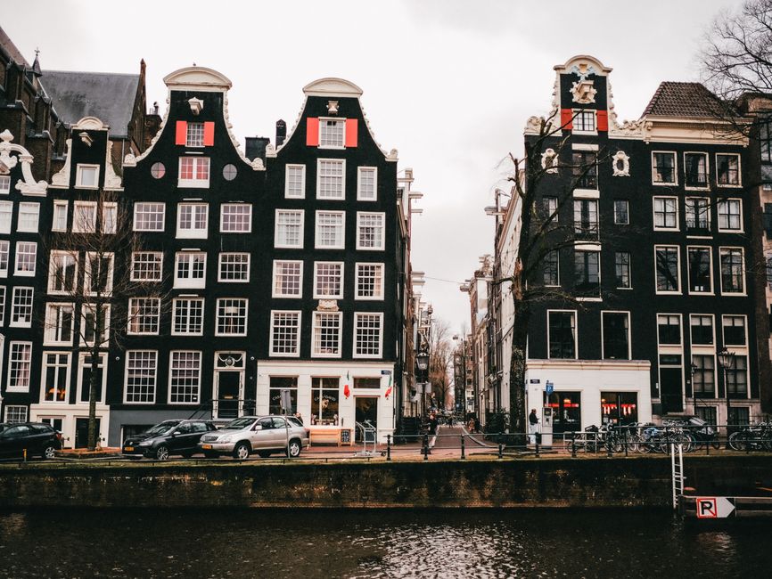 Charming Amsterdam canal houses with distinctive gabled facades along a waterfront.