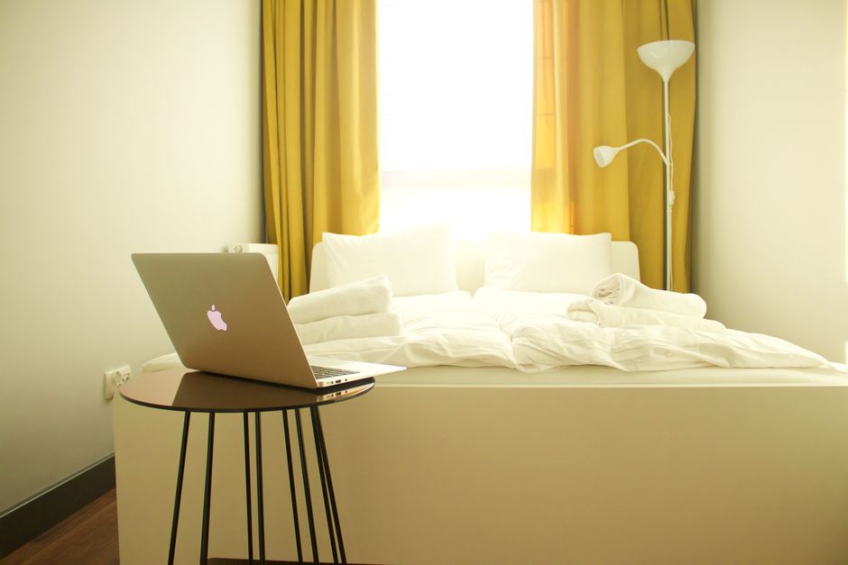 Cozy bedroom with a laptop, yellow curtains, and contemporary decor.