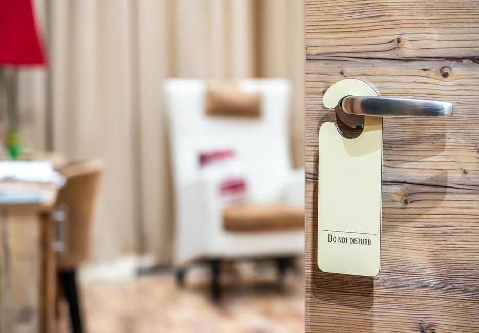 A hotel room door with a 'Do Not Disturb' sign, evoking a sense of privacy and relaxation.