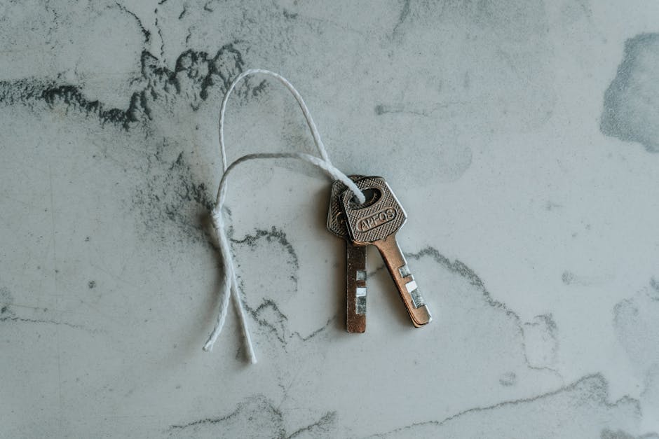 Two metal keys on a string against a marbled background, symbolizing security.