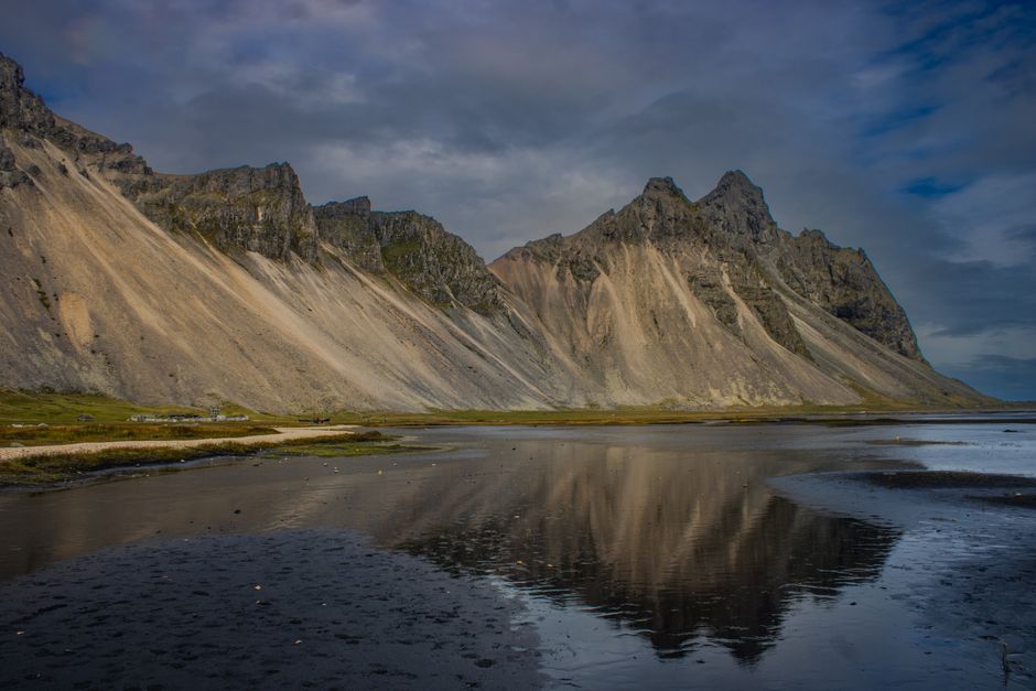 Breathtaking landscape of Vestrahorn mountain reflecting in a calm lagoon under a dramatic