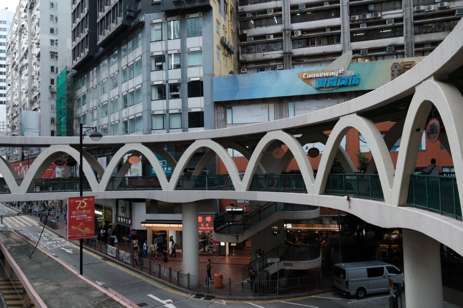 A busy urban street with an elevated walkway in a vibrant city area.