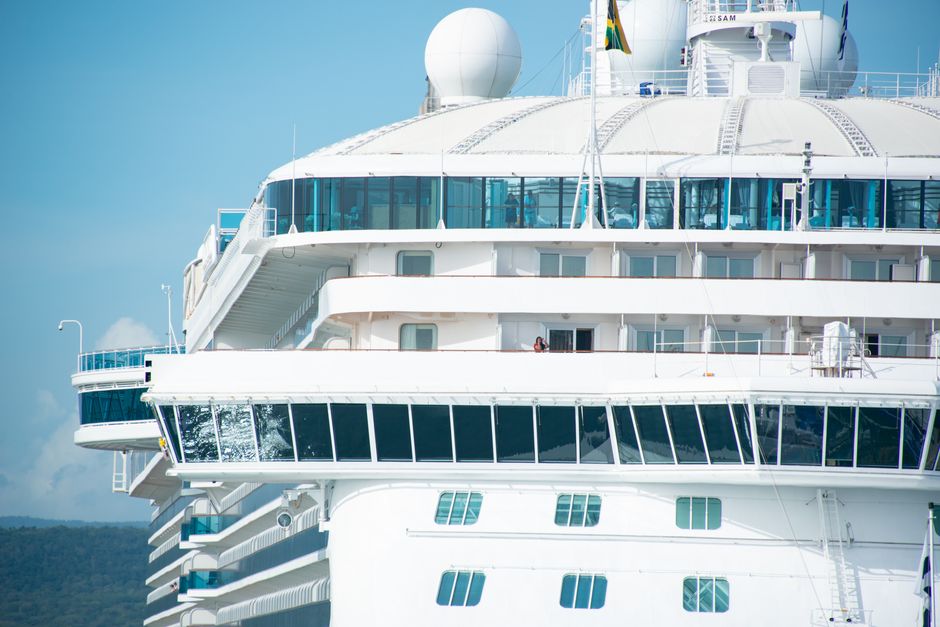 Detailed view of cruise ship exterior against a clear blue sky, showing windows and bright white structure.