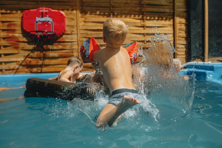 Children having fun splashing in an outdoor swimming pool during a summer day.