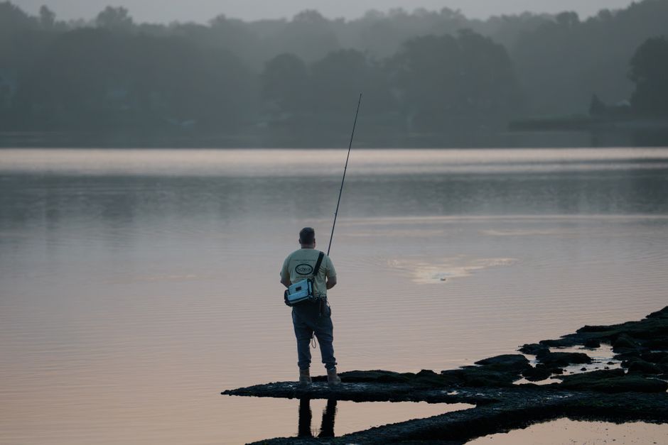 A tranquil scene of a fisherman at sunrise on a calm lake, encapsulating peace and solitude.