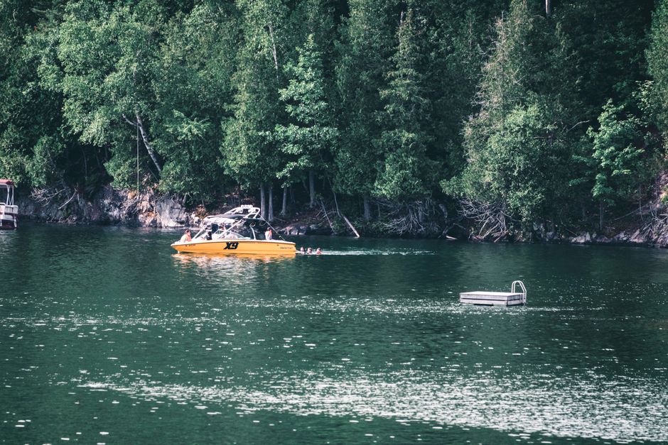 Enjoy a summer day boating on the serene lake surrounded by lush forests in Mont-Tremblant, Quebec.