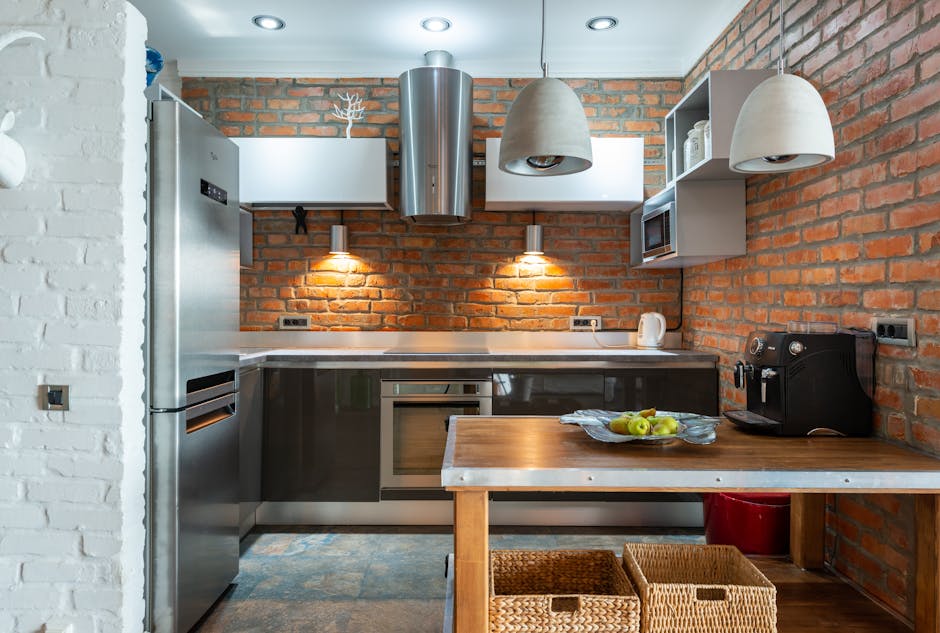 Stylish kitchen featuring exposed brick walls, modern appliances, and wooden table with fruit bowl.