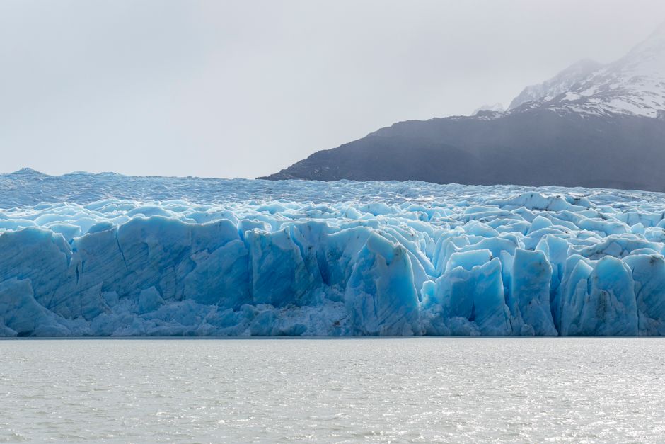 Stunning view of a glacier at Torres del Paine, showcasing icy blue hues and rugged landscape.