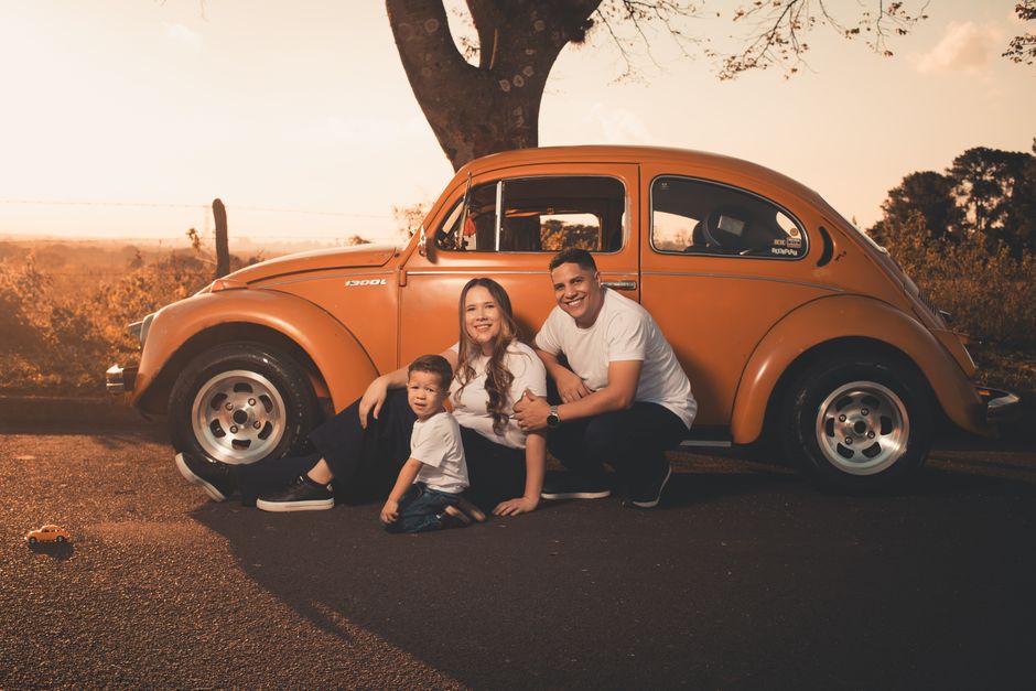 Warm family photo with a vintage orange beetle at sunset.