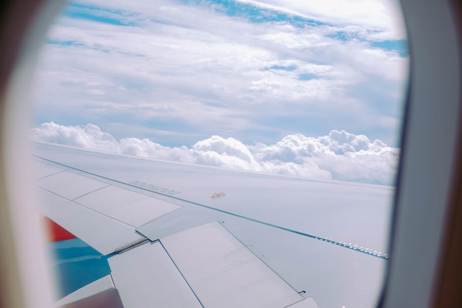 Serene view of fluffy clouds through an airplane window, capturing the essence of travel.