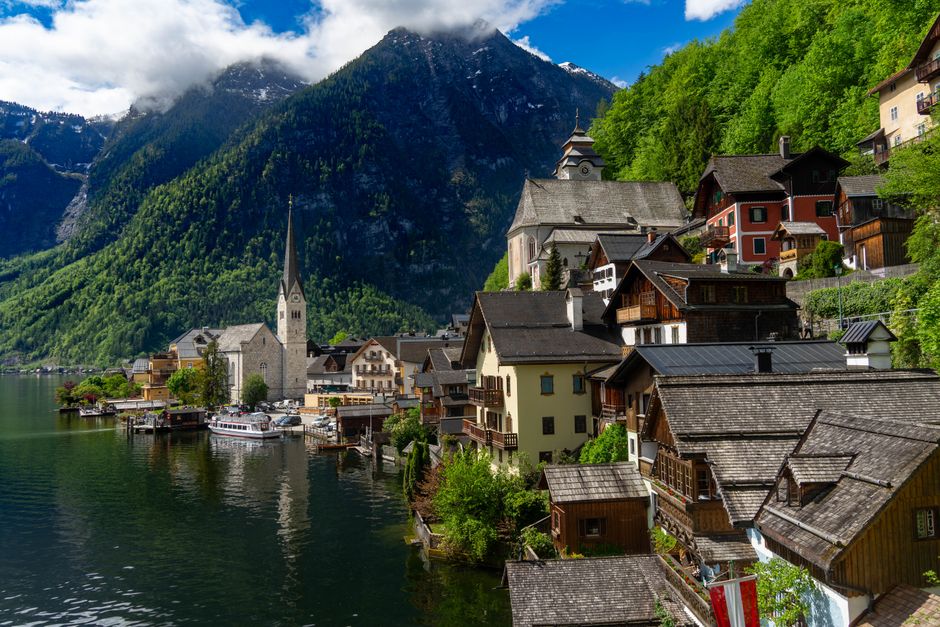 Scenic view of Hallstatt village nestled by a tranquil lake surrounded by mountains, in Upper Austria.