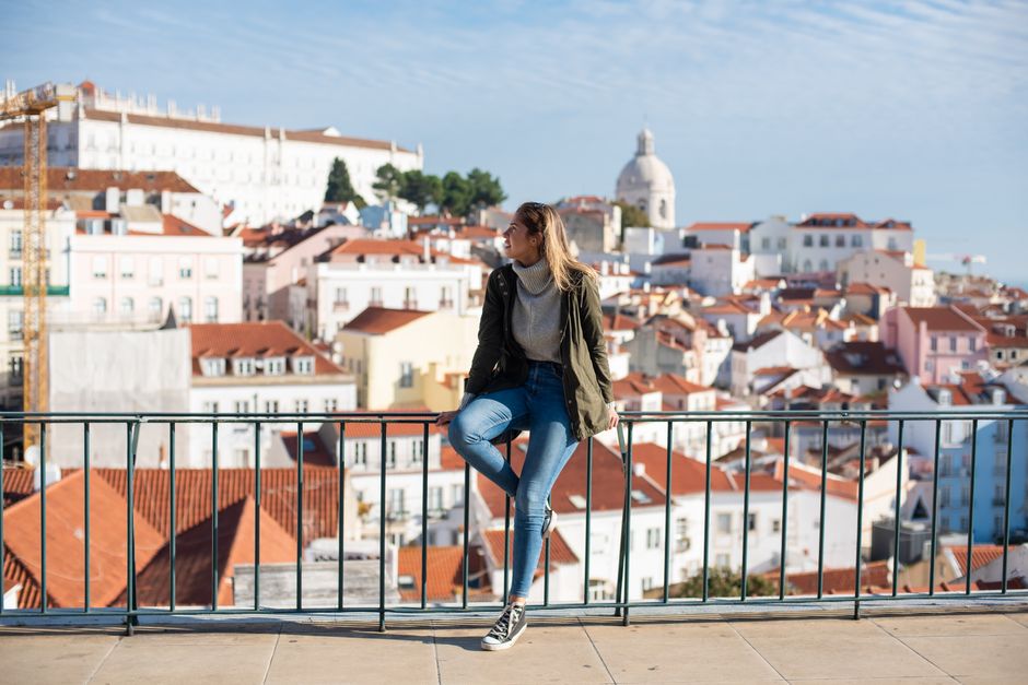 A traveler enjoys the view of Lisbon's colorful rooftops from a terrace.