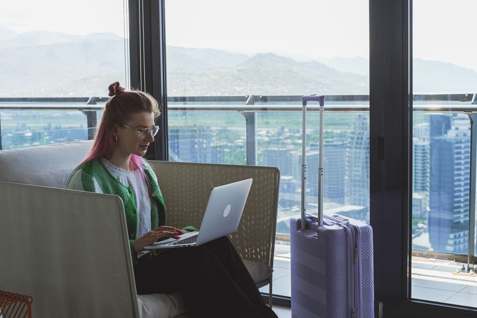 Woman working on a laptop in a hotel lounge with a stunning city view.