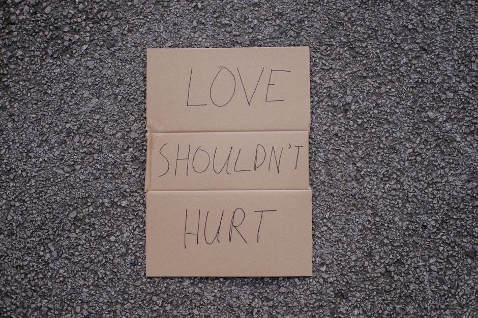 Top view of social slogan love should not hurt on cardboard placed on asphalt road on urban street